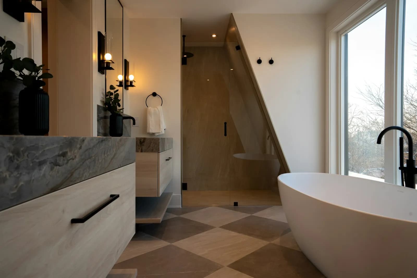 A bathroom in warm stone with a freestanding bath and walk-in shower