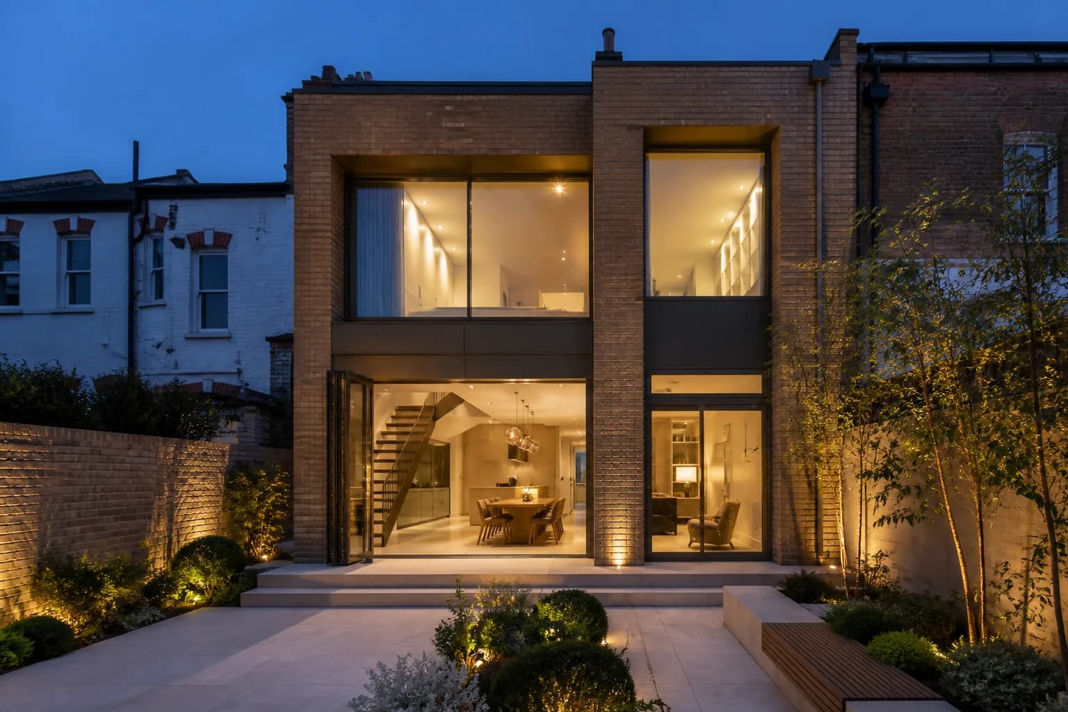A brick and glass double-height rear extension lit at dusk