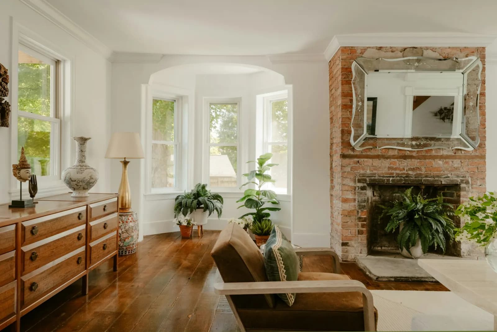 A renovated Victorian living room with an exposed-brick fireplace and bay window